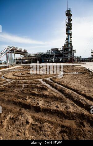 Grigio a colonna di distillazione su sole luminoso in corrispondenza di un cielo blu con nuvole sulla raffineria di petrolio pianta in un deserto. Foto Stock