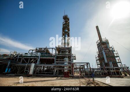 Grigio a colonna di distillazione su sole luminoso in corrispondenza di un cielo blu con nuvole sulla raffineria di petrolio pianta in un deserto. Foto Stock