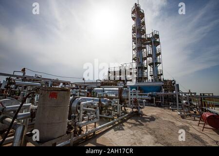 Grigio a colonna di distillazione su sole luminoso in corrispondenza di un cielo blu con nuvole sulla raffineria di petrolio pianta in un deserto. Foto Stock