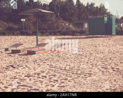 Spiaggia. Tre letti sotto l'ombrello. Green spogliatoio sullo sfondo del cottage Foto Stock