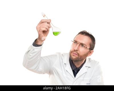 Medico maschio guardando attentamente nel liquido verde nel bicchiere. Isolato su bianco Foto Stock