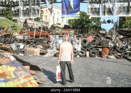 KIEV, UCRAINA - 5 agosto 2014: uomo in piedi vicino a un Euromaidan barricata su Heroyiv Nebesnoyi Sotni durante la rivoluzione e proteste sulla piazza Maidan, Foto Stock