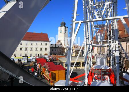 Vista da una grande ruota oltre il mercato di Natale nella Piata Mare a Sibiu in Transilvania, Romania Foto Stock