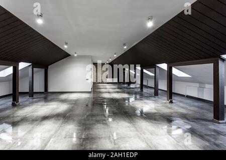 Vuoto non ammobiliato loft mansarda sala interna con colonne di legno e calcestruzzo bagnato pavimento sul livello del tetto in nero e stile whote colore Foto Stock