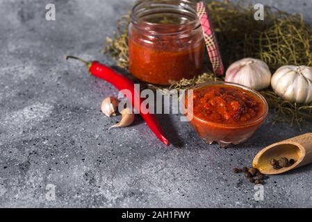 Tradizionale messicano, georgiano e arabo harissa pepe pasta su un cemento grigio Sfondo. Utile il cibo piccante Foto Stock