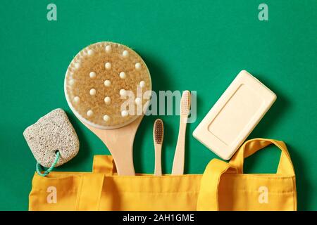 Concetto di rifiuti zero e la cura per l'ambiente. Prodotti tessili eco friendly sacchetti, sapone, spazzolino da denti di bambù, sapone accessori su uno sfondo verde. Vista superiore Foto Stock