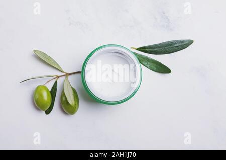 Naturale crema idratante con estratto di oliva sul marmo bianco tablem vista dall'alto. Foto Stock