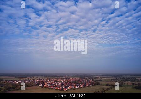White Piccole nuvole nel cielo blu su orizzonte profondo con un villaggio nel nord della Germania profonda pianura, vista aerea Foto Stock