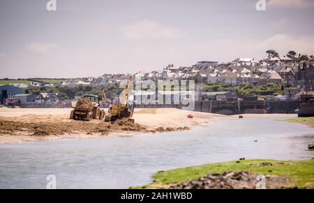 Movers terra e scavatori dragare e spostare la sabbia per pulire un canale nel fiume Camel guardando verso l'ingresso del porto di Padstow, Cornwall, Regno Unito. Foto Stock