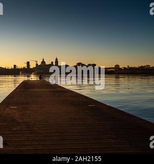 Maschio adulto kayaker spruzzi d'acqua con paddle mentre il kayak sul Lago Inferiore (Lago Inferiore) di fronte al suggestivo centro storico di Mantova. Foto Stock