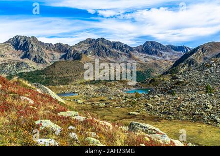 I colori dell'autunno, dominata dal rosso dei mirtilli, il blu intenso del cielo e il verde smeraldo delle acque dei laghi alpini Foto Stock