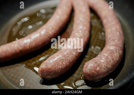 Tedesco bratwurst raw giacente in grasso in una padella Foto Stock