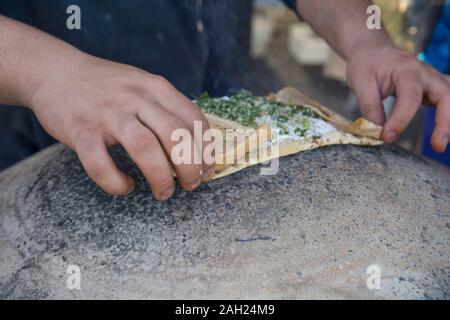 L'uomo la cottura di un tradizionale Drusi Pane Pita, su un Saj o Tava Foto Stock