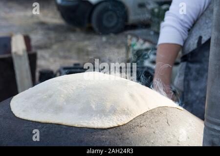 L'uomo la cottura di un tradizionale Drusi Pane Pita, su un Saj o Tava Foto Stock