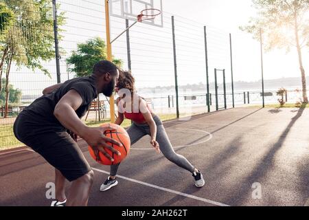 Attività all'aperto. African giovane giocare a basket sulla corte dribbling in motion felice Foto Stock