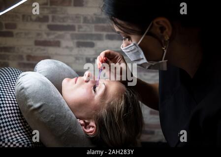 Applicazione di colla sulle ciglia, fissaggio. Procedura di personalizzazione delle extension delle ciglia. La donna nel salone di bellezza. La bellezza e la cura di sé Foto Stock