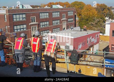 Lavori pericolosi. NYC MTA transito di lavoratori guardare lontano come #7 elevato alla metropolitana treno li passa a Woodside, Queens, a New York City. Foto Stock