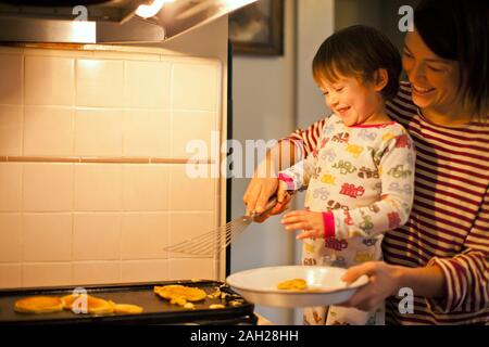 Madre e figlio cucinare frittelle insieme. Foto Stock