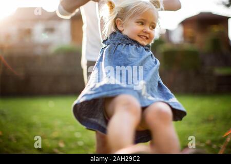 Giovane ragazza che gioca con la madre nel cortile posteriore Foto Stock