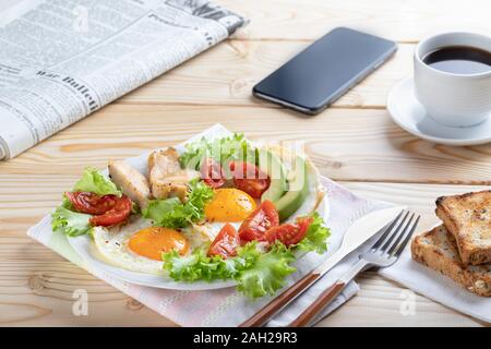 Una sana prima colazione di lavoro in unione o in stile americano con uova fritte, verdure ed erbe aromatiche. Close up Foto Stock