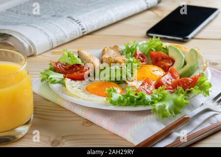 Una sana prima colazione di lavoro in unione o in stile americano con uova fritte, verdure ed erbe aromatiche. Close up Foto Stock