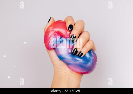 Mani con manicure nero tenendo il fango in blu e rosa colori vibranti Foto Stock