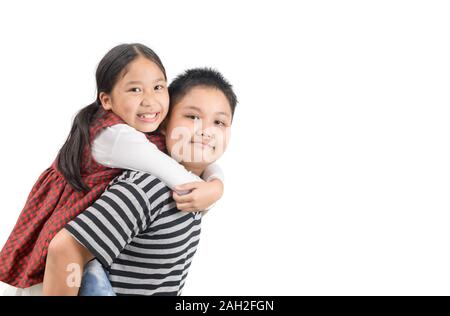 Fratello dando piggyback ride a suor isolati su sfondo bianco, felice e giocare insieme concetto Foto Stock