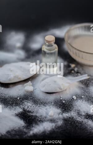 Maschera per il viso o il viso pack di bicarbonato di sodio in un recipiente di vetro su una superficie di legno lungo con polvere e alcuni di olio di noce di cocco in un vetro trasparente bottiglia. Utilizzato per Foto Stock