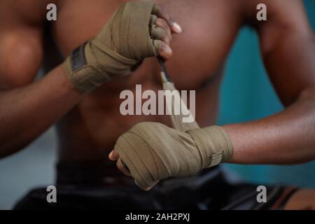 Close-up di africani boxer muscolare indossando un bendaggio alle mani e preparazione per la formazione sportiva Foto Stock