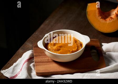 Purea di zucca in una ciotola su sfondo di legno Foto Stock