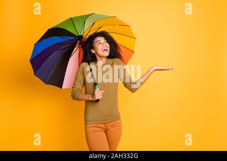 Foto di ondulato bella carino affascinante bella ragazza dolce entusiasta per la cattura di gocce di pioggia caduta sulla sua mano azienda ombrellone che si nasconde sotto isolate su Foto Stock