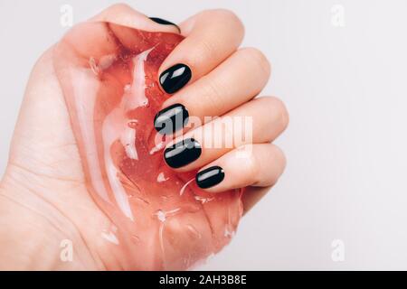 Mani con manicure nero trasparente di contenimento limo Foto Stock