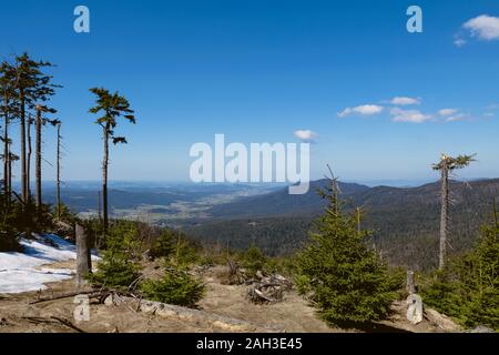 La vista dalla cima di una montagna nella valle con le nuvole nel cielo blu e bellissimi alberi verdi e un sacco di rocce Foto Stock