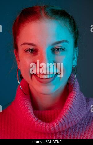Sorridenti, vicino. Caucasian ritratto di donna isolato su gradiente di sfondo per studio in luce al neon. Bellissimo modello femminile con i capelli rossi. Concetto di emozioni umane, l'espressione del viso, vendite, annuncio. Foto Stock