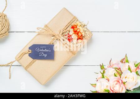 Mockup kraft scatole regalo con tag in bianco sullo sfondo di legno con buon San Valentino testo sulla cartolina. Mock up per un design elegante. Appartamento laici vista superiore Foto Stock