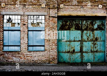 chiuso porta doppia in metallo e finestre di un magazzino abbandonato in decadimento Foto Stock
