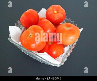 Una ciotola di vitigno freschi pomodori cresciuti in un taglio ciotola di vetro. Foto Stock