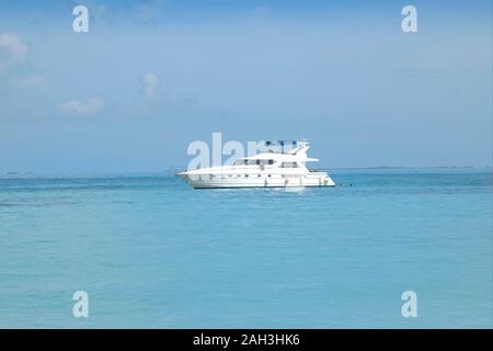 Super lussuoso yacht a motore spento davanti a una bianca spiaggia Caraibica. Spiaggia Bianca e cristallino mare turchese. Isla Mujeres Messico. Foto Stock