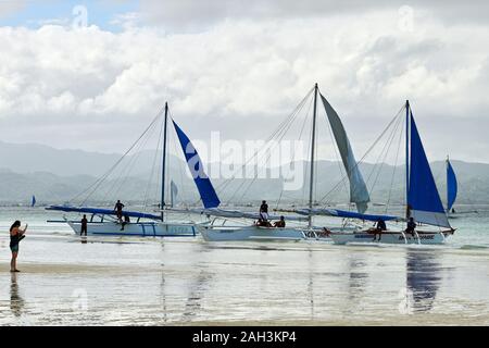 Il Boracay, Aklan Provincia, Filippine - Gennaio 3, 2019: Barche a vela parcheggio lungo la spiaggia di sabbia bianca con le vele verso il basso a causa delle cattive condizioni meteorologiche Foto Stock