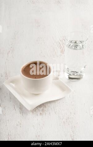 Il caffè turco servito con un bicchiere di acqua su un tavolo di legno Foto Stock