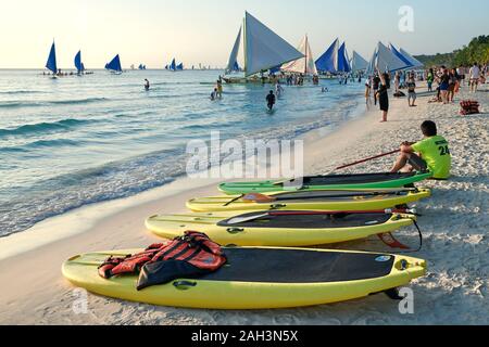 Il Boracay, Aklan Provincia, Filippine - 13 Gennaio 2019: Tramonto alla spiaggia bianca con paddle boards e barche a vela in attesa per i turisti Foto Stock