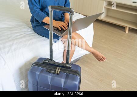 Chiusura del freelancer femmina utilizzando laptop accanto alla valigia Foto Stock