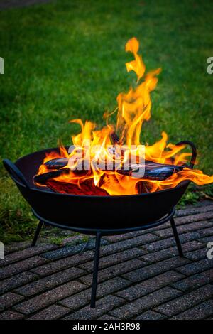 La realizzazione di un incendio in un incendio ciotola con la combustione di legna, bruciore e di colore arancio fiamme rende è bella e calda al di fuori Foto Stock