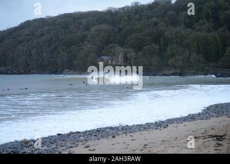 Surfisti a Oxwich Bay con St Illtyds chiesa nel bosco sfondo, Gower Foto Stock