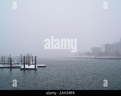 Nuvole appendere bassa su un nebbioso giorno con calma le acque in un marina. Foto Stock