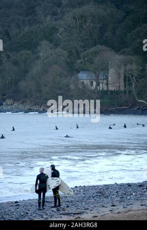 Surfisti a Oxwich Bay con St Illtyds chiesa nel bosco sfondo, Gower Foto Stock