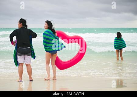 Il Boracay, Aklan Provincia, Filippine - 3 Dicembre 2019: tre donne asiatiche, avvolti in teli da spiaggia, stando in piedi presso la spiaggia tenendo un cuore rosso anello Foto Stock