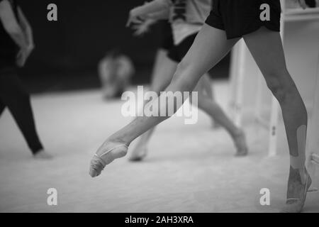 Gambe di ginnasti in movimenti coreografici in una sala prove durante il corso di formazione Foto Stock