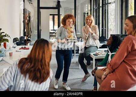 Felice imprenditrice che serve cibo da asporto di colleghi in ufficio Foto Stock