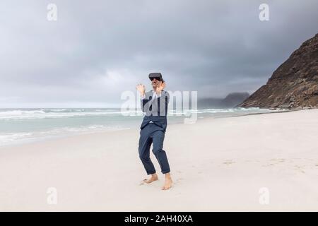 Imprenditore utilizzando occhiali VR sulla spiaggia, Nordhoek, Western Cape, Sud Africa Foto Stock